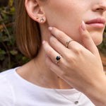 Green emerald cut sapphire ring on Shoham in front of greenery