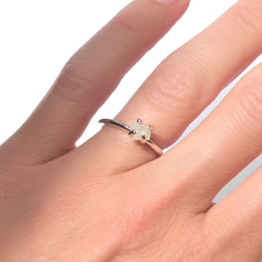 Raw diamond engagement ring in a delicate setting of 14k white gold and four prongs.