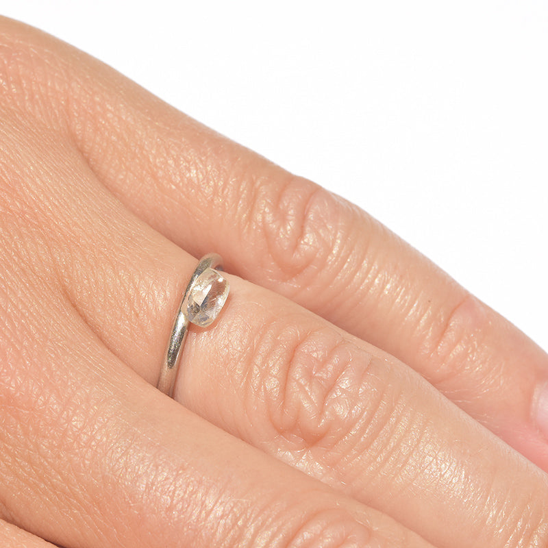 Rough diamond in a dodecahedral shape on a hand next to a minimalist platinum wedding band