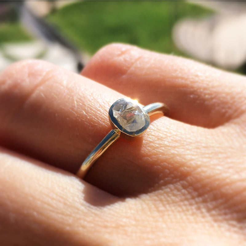 The Ora ring a bezel raw diamond engagement ring on a hand in the sunlight.